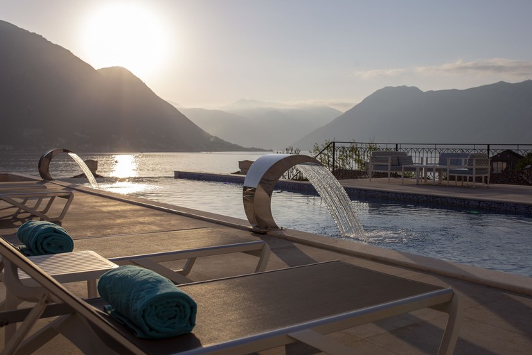 Loungers at the infinity pool at Huma Kotor Bay Hotel & Villas, with views of the Bay of Kotor and the mountains