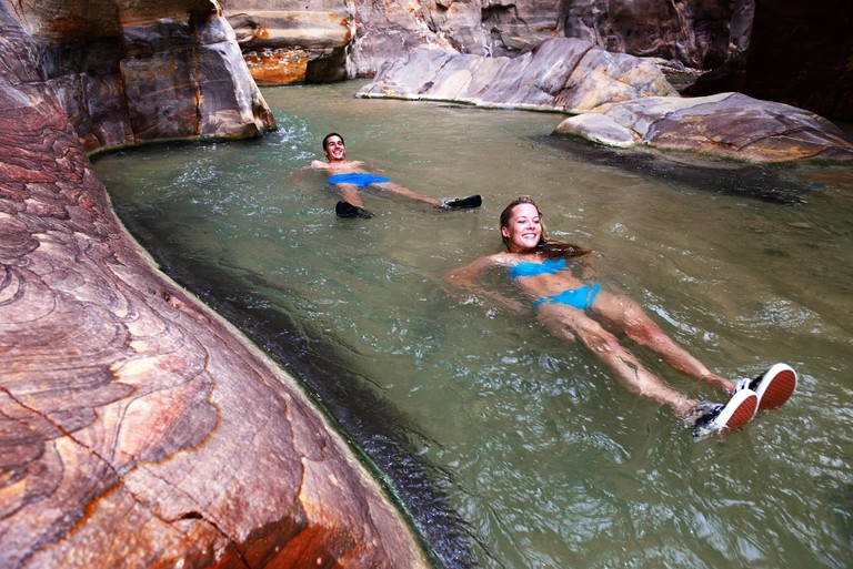 Young couple floats at the canyon of Wadi Mujib, Jordan