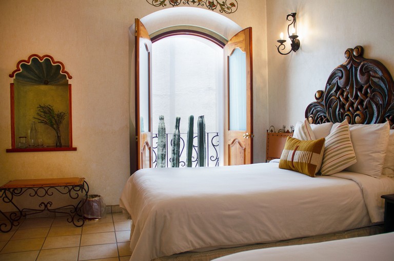 A twin room with cactus trimmed balcony and ornated wood headboards at Los Pilares Hotel