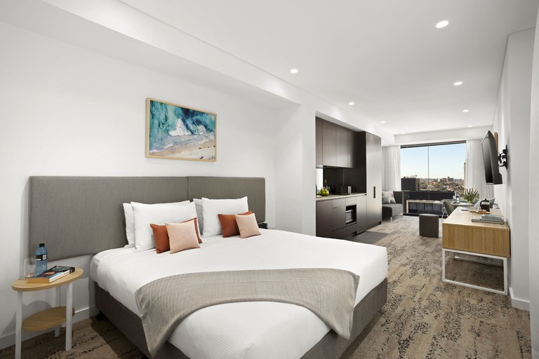 Long, modern studio with king bed, kitchenette, seating area and floor-to-ceiling windows with city views at Quest North Sydney
