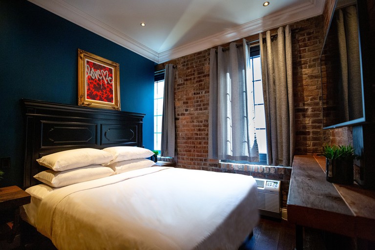 A bed and wooden desk in a bedroom with an exposed brick at the Sohotel, Lower Manhattan
