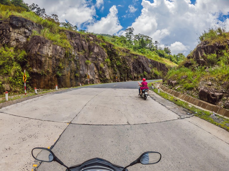 Motorcyclist rides on a serpentine road in cloudy weather. Vietnam, Dalat