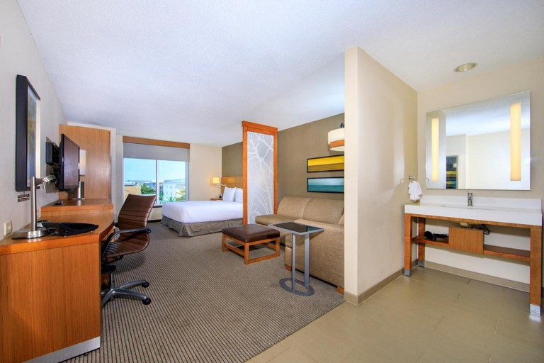 Double bed, sofa, sink, desk, desk chair and TV in a Hyatt Place Dewey Beach suite