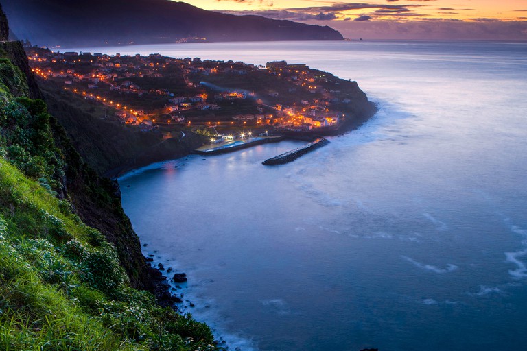 City lights twinkling in the town of Ponta Delgada, which juts out into the ocean, in the Azores at sunset