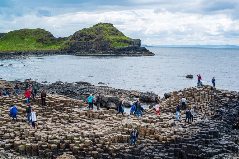 Tourists stop on the stone columns at the Giant's Causeway