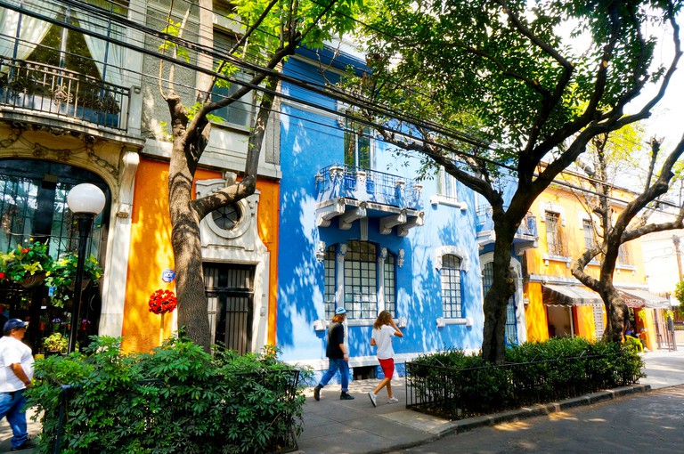Two tourists walk past the colourful shops and homes in Calle Colima in the Roma neighborhood