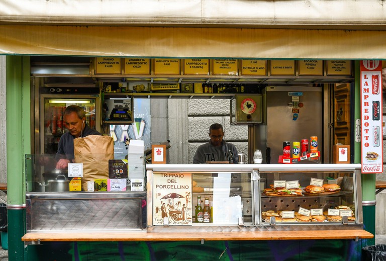 Men cooking lampredotto tripe sandwiches in the historical street food kiosk "Trippaio del Porcellino" in the centre of Florence, Tuscany, Italy