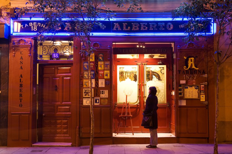 A person stood outside the doors of Casa Alberto in Madrid at night