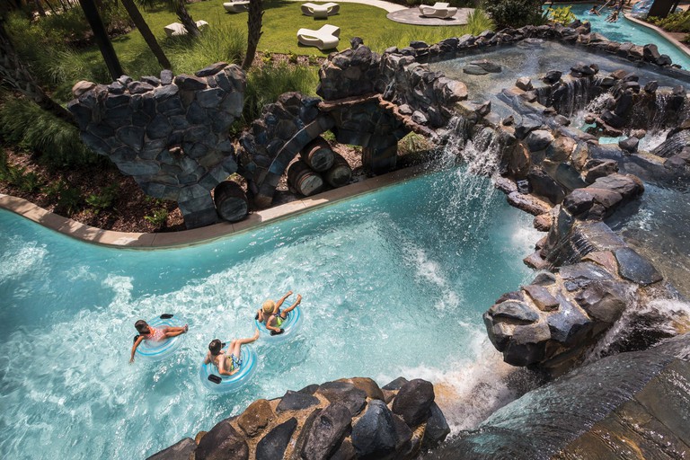 An outdoor lazy river swimming pool at Four Seasons Resort Orlando at Walt Disney World Resort, with a waterfall