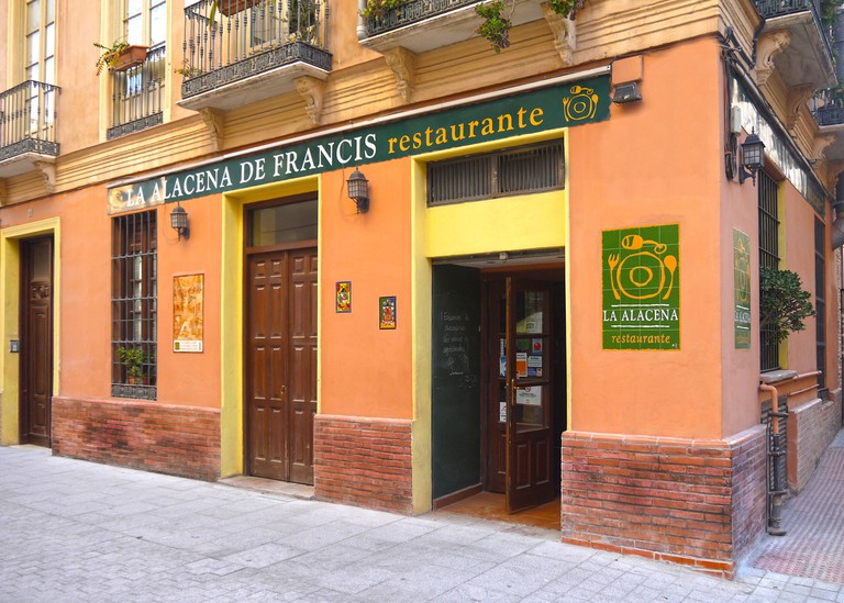 The peach and brick exterior of La Alacena de Francis restaurant in Málaga