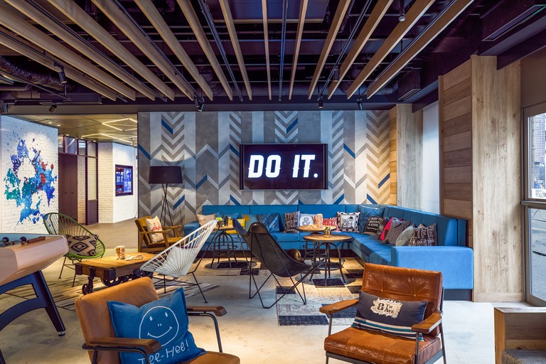 Spacious sitting area at Moxy Tokyo Kinshicho by Marriott with leather chairs, blue sofa and blue geometric wallpaper