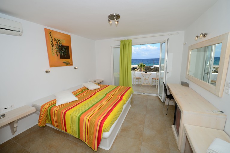 A bed with colourful bedspread and a balcony in a guest room at Paradise Beach Resort