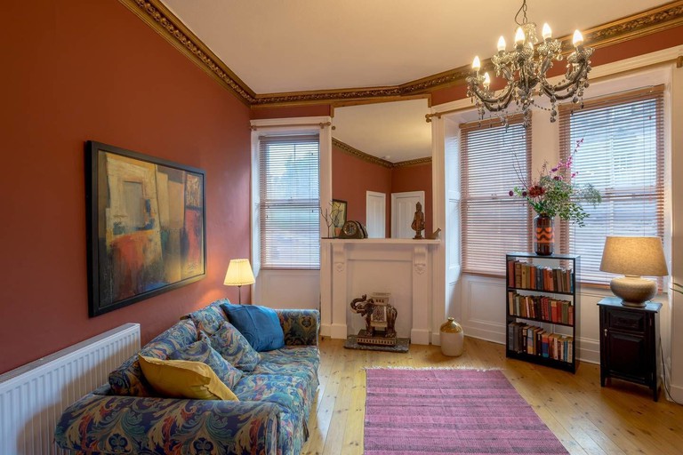 A cosy room at Unique Royal Mile Apt - Relive Music History with a bookshelf, chandelier and an abstract painting over a sofa