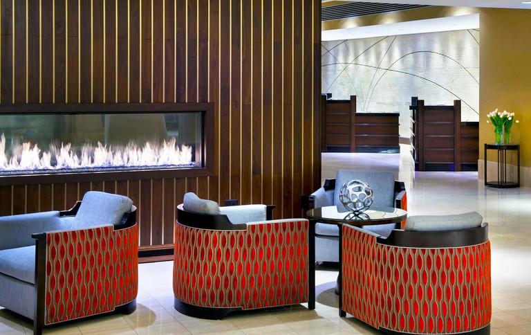Four red and light blue armchairs in front of an electric fireplace at Courtyard by Marriott Newark Liberty International Airport