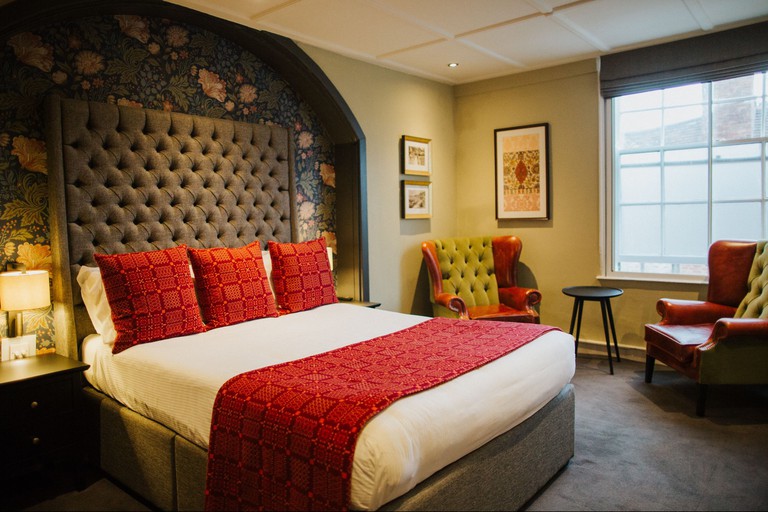 Room at the Globe has a floral feature wall, red and white bedding and plush leather seating