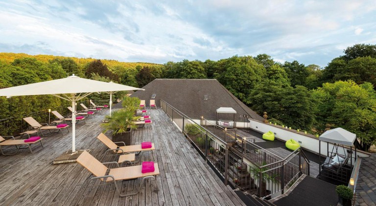 Sunbeds on the rooftop deck of Nells Park Hotel, surrounded by trees, in Trier