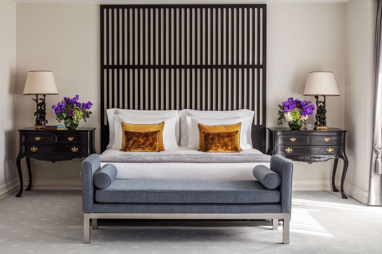 Double room at Tivoli Avenida da Liberdade features a tall black headboard, plush gold cushions on the bed and antique side tables