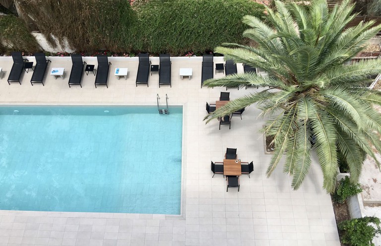 An aerial view of the minimal and modern pool area at Athens Coast Hotel