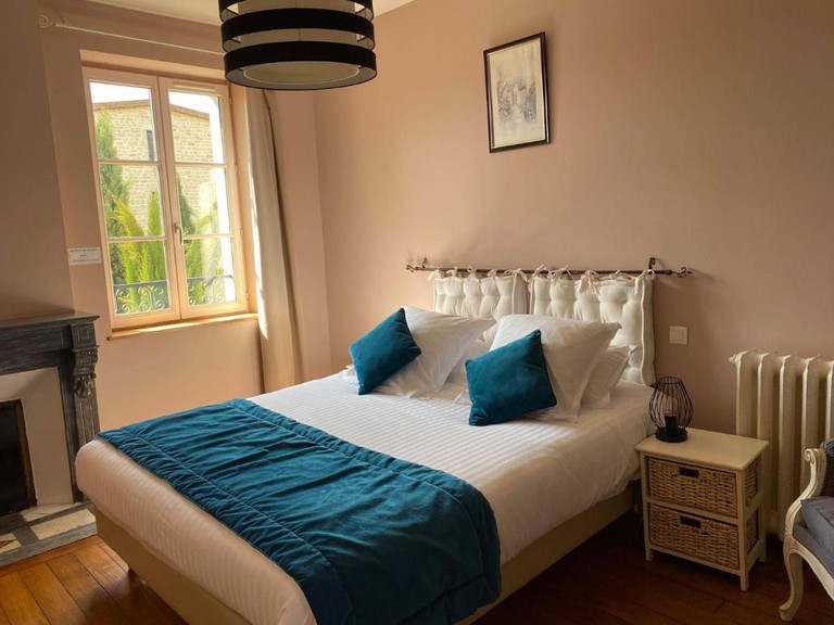 A cream and bright bedroom at Hôtel de la Vinaigrerie with a white and blue double bed