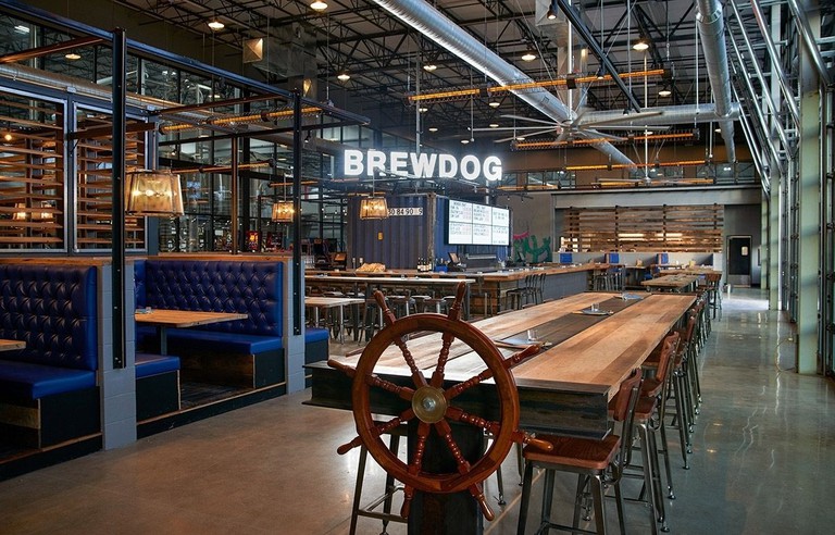 Eating and drinking area of DogHouse Hotel and Brewery with blue leather booths and large wooden tables