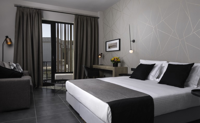 A contemporary guest room decorated in shaded of white, grey and black at Azur Suites