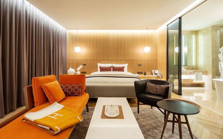 A stylish suite at Hotel28 Myeongdong with a double bed, orange chaise lounge and an ensuite