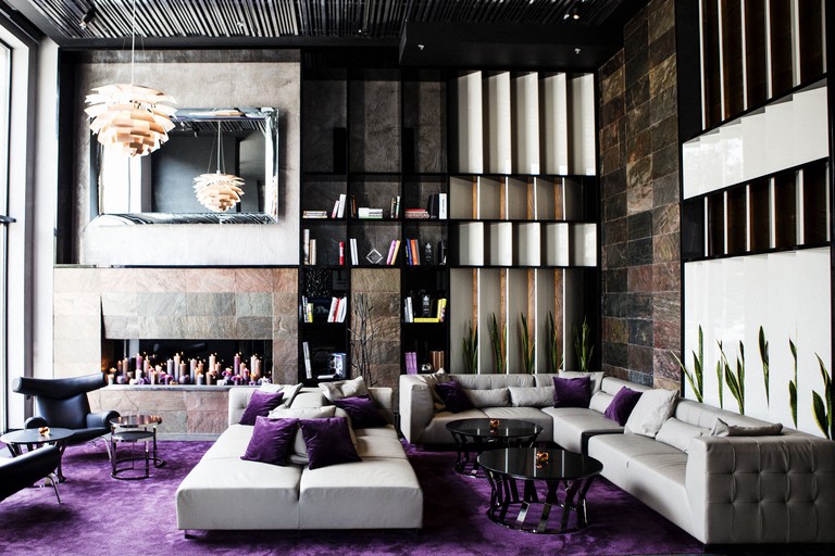 Large couches and seating, with bookshelves, purple carpeting and potted plants, in the stylish lobby at 11 Mirrors Design Hotel in Kyiv, Ukraine