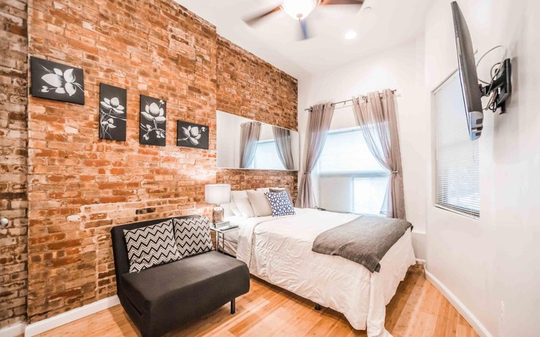 A simple hotel room with an exposed-brick wall and double bed at the Chelsea Inn Hotel.