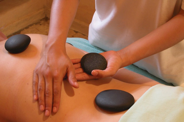 A guest having hot stone therapy in the spa at Hotel Mision del Sol