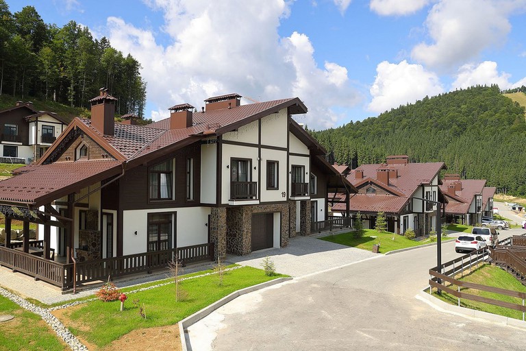 The exterior chalet-style Mountain Residence, with forest and countryside around it, in the Carpathian Mountains in Ukraine