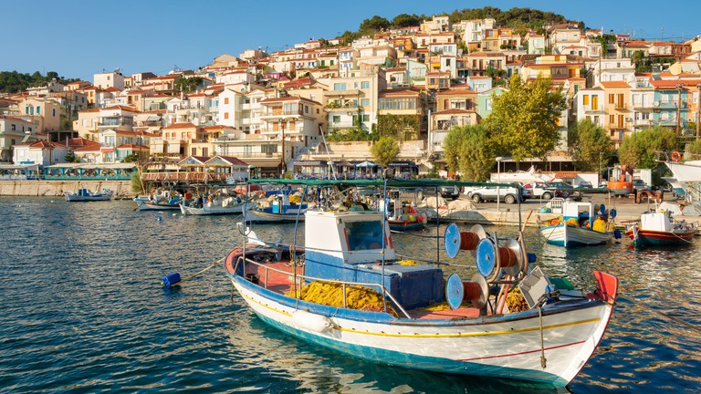 Panorama view of the picturesque port with traditional wooden fishing boats and the village of Plomari, Greece