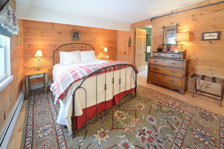 A wood-paneled double bedroom with an iron bedstead at The Springwater B&B