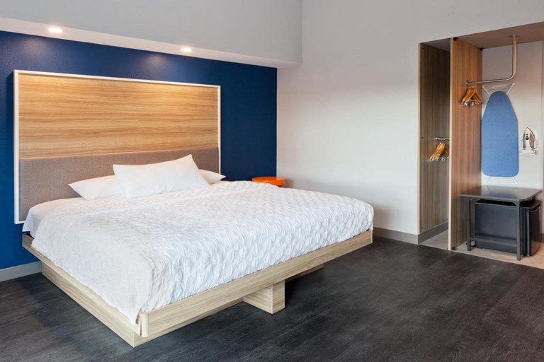 A double room at the Tru by Hilton Auburn has modern, chic design, grey floors, blue and white walls and a small wardrobe