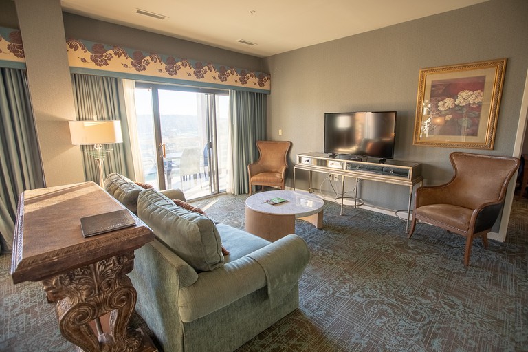 Sofa and two leather armchairs in neutral-toned room with large TV at Turf Valley Resort