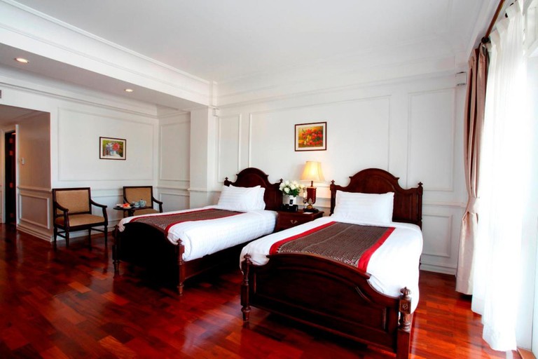 A guest room with two twin beds and polished wood floors at the Dhavara Boutique Hotel