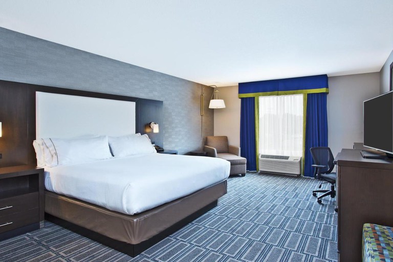A large bed in a Holiday Inn Express & Suites Ann Arbor West room, facing a flat-screen TV