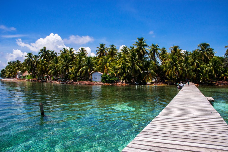 Jetty and palm trees on tiny Tobacco Caye, an island off the coast of Belize