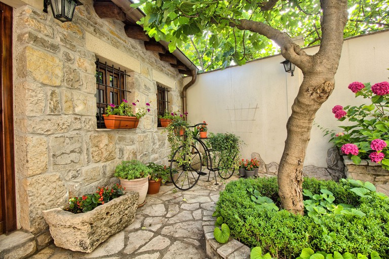 The stone-wall exterior and paved garden of Villa Fortuna in Mostar
