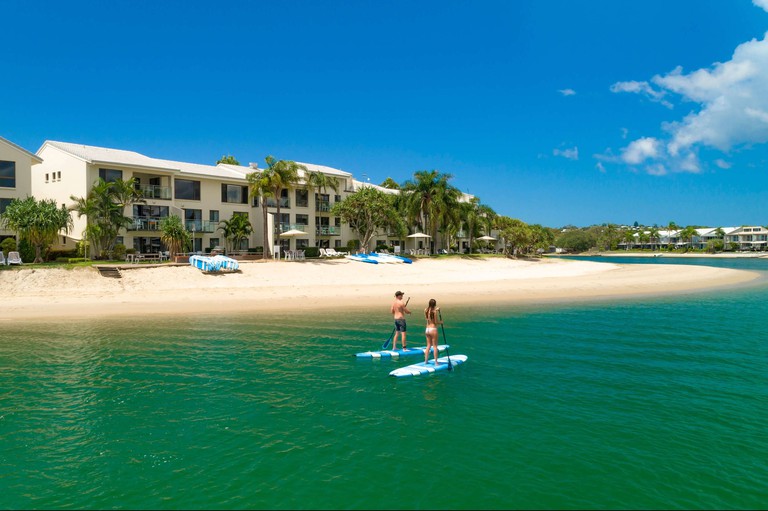 Couple paddle boarding at Culgoa Point Beach Resort, Queensland, Australia