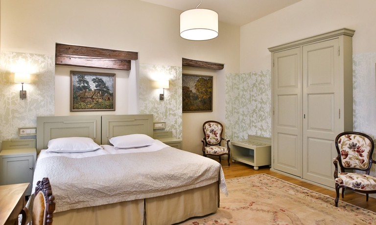 A room at Hotel Antonius, with a large bed, and pastoral paintings on the walls
