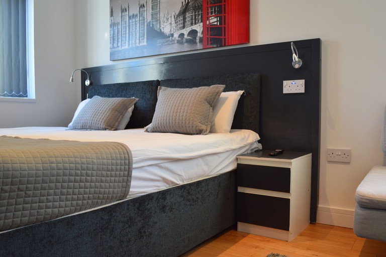 Modern room with black bedhead, wood floors and large photographic print of London at the Bell Gate House