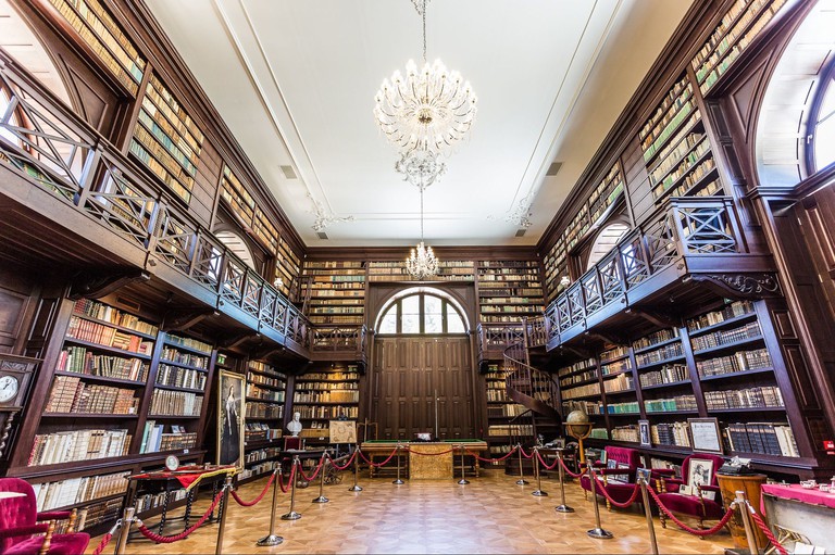 Old-world library at Chateau Appony in Slovakia with walls lined with books and a chandelier