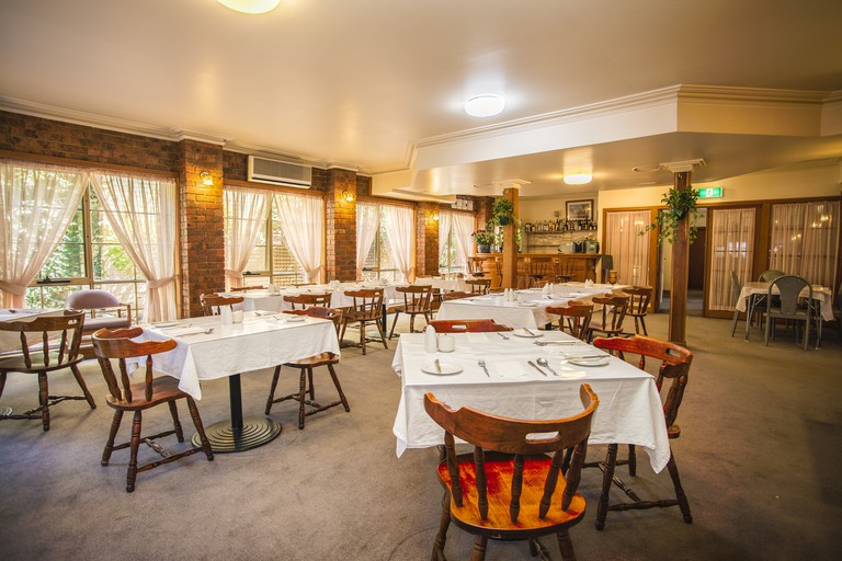 The casual restaurant with exposed brick, crown moulding and wooden chairs at the St Georges Motor Inn