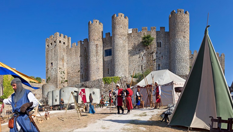 A Medieval fair, with people dressed in costumes, outside the Castle of Óbidos