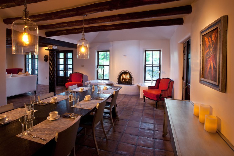 Palacio De Marquesa tile floors in chic dining space with fireplace and exposed beams