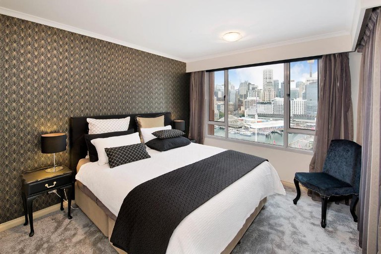 Snug bedroom with stylish patterned wallpaper, dark accents and panoramic views of Sydney