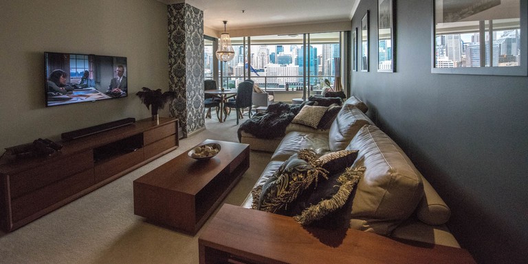 Leather and wood furnishings in large living room with skyline views at the Darling Harbour Getaway holiday apartment