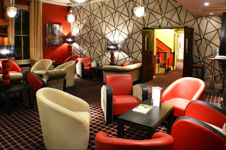 Belmont Hotel lounge with red and tan armchairs and walls and carpets in bold colours and patterns