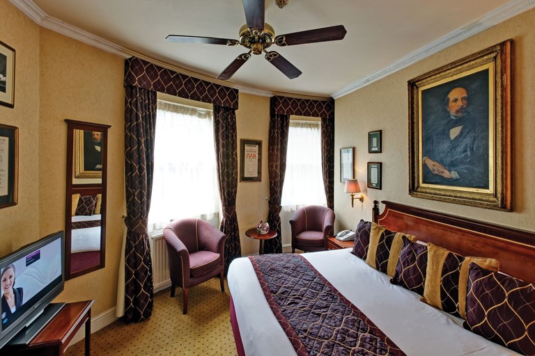 A traditional room at the Grange Blooms Hotel with an old-style portrait over the bed