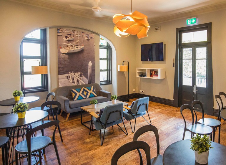 Glenferrie Lodge dining room with wood floors, dark grey tables and chairs and a grey couch